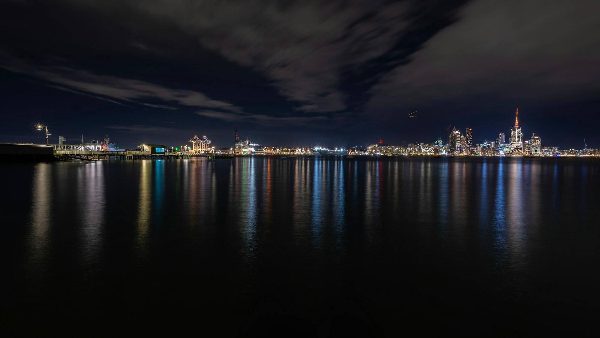 Auckland's lit-up city skyline reflected in the Waitematā Harbour at night