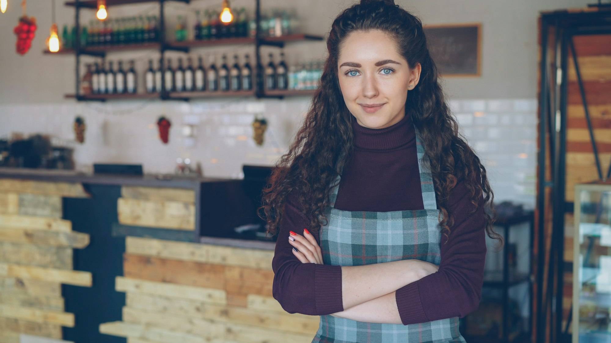 A smiling cafe owner standing in her coffee shop